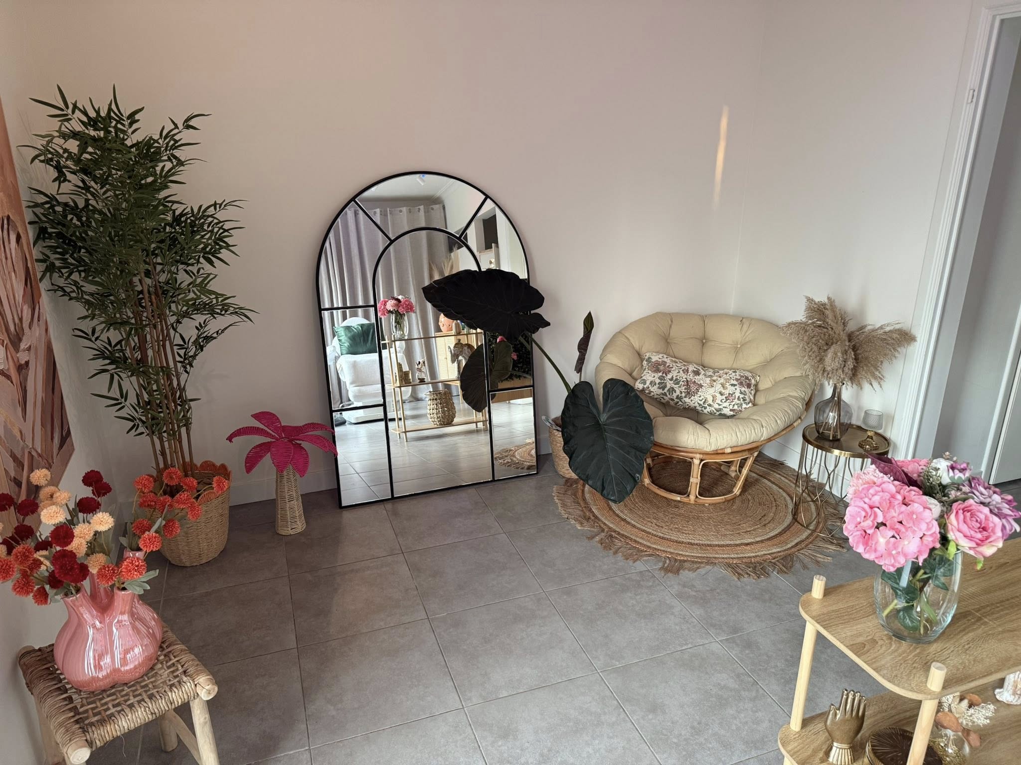 Rustige beauty-studio met rotan stoel, bloemen en grote boogspiegel